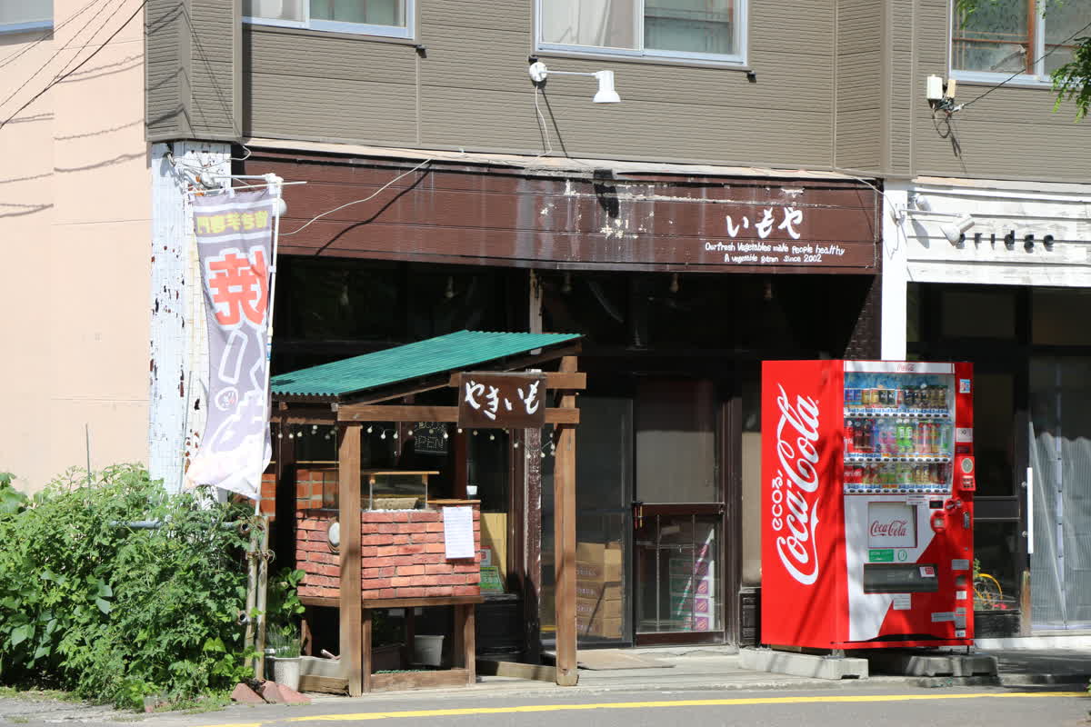 焼き芋いもや平岸店の外観。茶色の看板と店頭の焼き芋売り場が目印です。